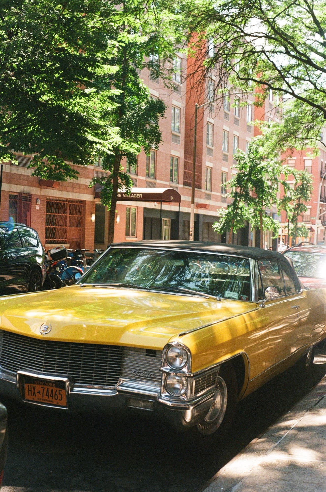 Film frame on Fujifilm 400 — a yellow Cadillac convertible parked on a tree-lined New York street